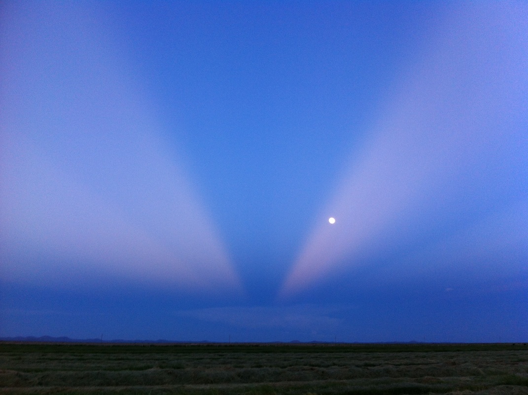 Sun rays across the sky with full moon in background